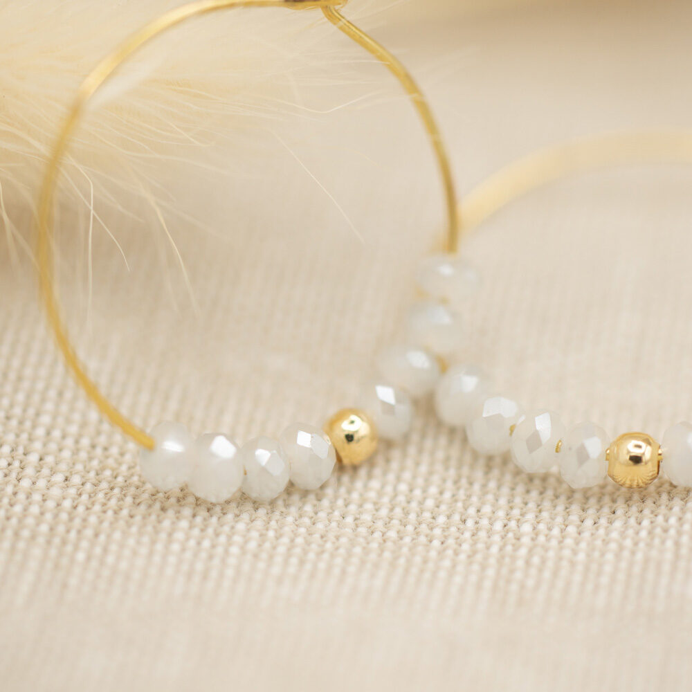 Goldene Creolen mit facettierten Glasperlen in Weiß Detail